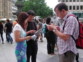 '路人仔细阅读传单,了解法轮功真相'