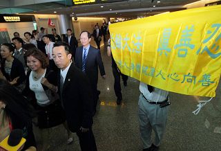 黄华华所带领的广东团一出海关,即面对法轮功学员在桃园机场大厅打出“法轮大法 真善忍”、“停止迫害法轮功”等横幅。