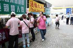 “香港青年关爱协会”负责人之一林国安(穿粉红横条文者)在现场指挥冲击法轮功真相点,他与中国井冈山市一名特聘政协委员“同名同姓”,有消息称此人就是周永康阵营专程从中国派来香港负责冲击法轮功真相点的中共特工。