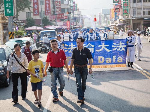 '甲仙区区长李元新(前排右一)与商圈理事长(前排右二)为法轮功队伍踩街开路,赞叹法轮功对观光客吸引力特别强,活络地方经济。'