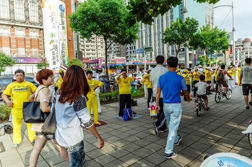 环绕明诚公园四周展开“功法长城”,演示法轮功五套舒缓优美的动作;群众放慢脚步观赏。
