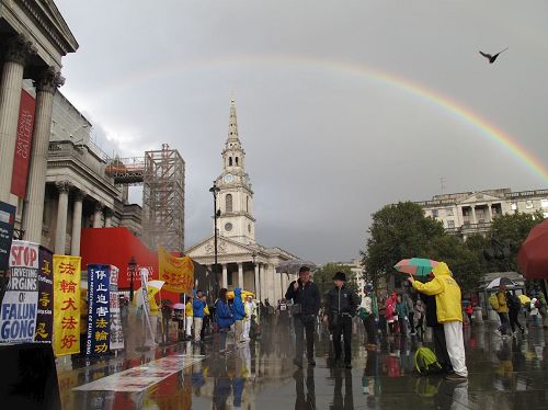 '图16:二零一六年十月一日下午,法轮功学员在特拉法加(Trafalgar Sqare)北平台举行集体炼功和讲真相活动时,天空中出现的彩虹'