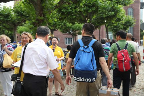 一队队中国人从法轮功学员的摊位旁走过,法轮功学员善心告诉他们真相。