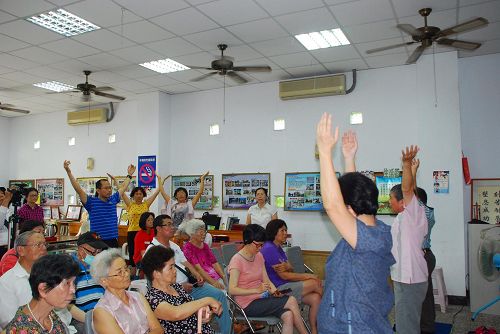 观看着法轮功学员的功法演示,有的民众当场跟着学员学炼动作。