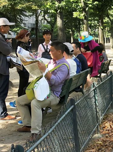 '图4：大陆游客在巴黎埃菲尔铁塔下休息时，认真阅读退<span
