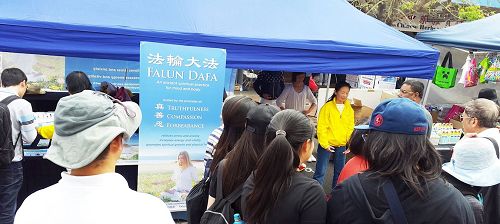 '图4:法轮功学员的展位吸引了很多民众前来了解功法'