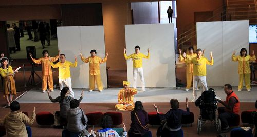 '图1:法轮功学员在舞台上演示五套功法,民众模仿学炼'