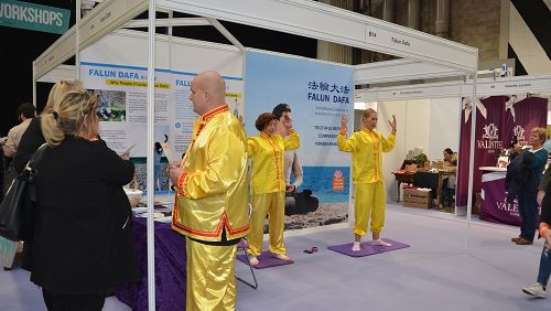 图:1法轮功学员在英国伯明翰市举办的“身、心、灵健康节”上设立法轮大法展位,向人们展示功法,分发真相传单。