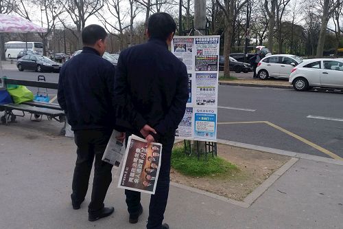 '在巴黎埃菲尔铁塔旁的法轮功真相点上，两名中国大陆游客在接过《法轮功真相报》和大<span