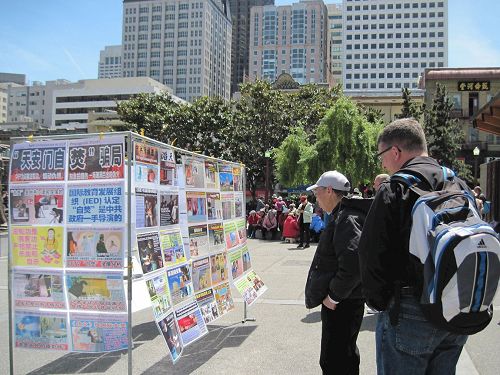 '图5~6:民众正在阅读揭示中共迫害法轮功,及活摘法轮功学员器官倒卖的真相展板。'