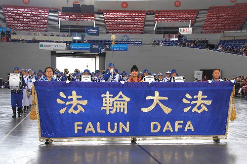 '图6:当这个由一百四十多位法轮功学员组成的队伍在“法轮大法”横幅的引领下,出现在体育场的一霎间,场观众掌声雷动。一曲撼动人心的《凯旋》演奏过后,主办方特意要求再加演一首《神圣的歌》。'