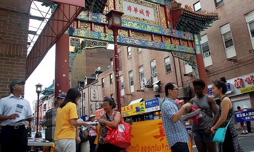 '图3:法轮功学员在费城中国城向过往民众介绍什么是法轮功。'