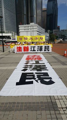 '图5~6:香港法轮功学员于三十日早晨,在爱丁堡广场集体炼功,并在正面遥对习*近*平住宿的海景万丽酒店方向,打出“法办江泽民”的巨型横幅。'
