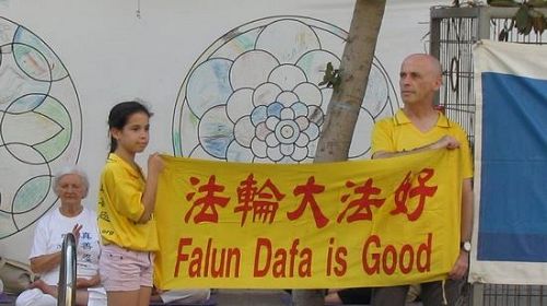 '图1:法轮功学员在中使馆前手持“法轮大法好”横幅'