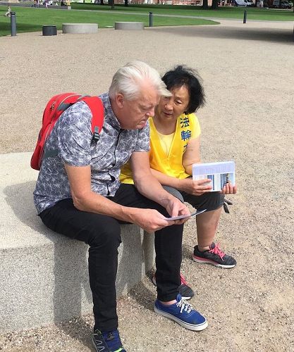'图4:这位先生和学员交流了一会儿,了解到法轮功祛病健身有奇效,而且道德高尚,他很想知道更多的信息,对学员说:“我们能坐下来继续交谈吗?”'