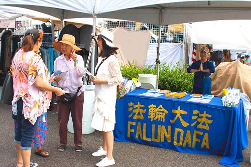'图1:民众在法轮功真相展位前了解真相'