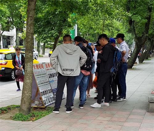 '图:法轮功学员在台北国父纪念馆的园区内的真相点吸引大陆游客了解真相'