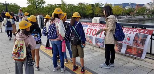 '图10:这位教师(右)正在向学生们讲解真相横幅的内容。'