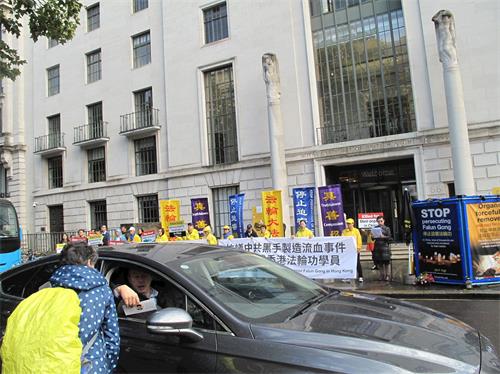 '图3:英国法轮功学员在伦敦中使馆前集会反迫害,路人和司机接过法轮功真相传单。'