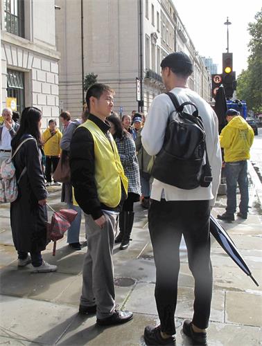 '图5:十月一日,反迫害集会结束后,英国学生约翰(右)与法轮功学员交谈进一步了解真相。'
