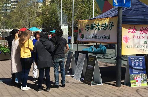 '图5:大学生马格赛、霍尔和他们的几位同学在展位前了解真相并签名。'