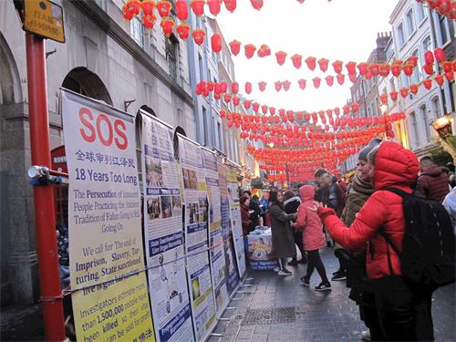 '图10:二零一九年二月十日晚,一对来自立陶宛(Lithuania)的母女在伦敦唐人街认真了解法轮功真相'