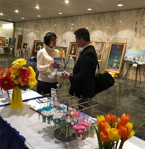 图4~5:前来参观画展的民众正在聆听学员讲述法轮功真相。