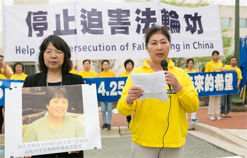 图5:于敬在集会上发言,她身旁的女士手捧法轮功学员杨晓辉的遗照。
