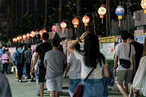 '图3:庆祝和迎接“世界法轮大法日”的到来,五月十一日华灯初上,法轮功学员们在瑞丰夜市张灯结彩,摆好真相长城,让路过民众了解真相。'