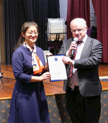 '图2:二零一九年五月三日,悉尼帕拉马塔市(City of Parramatta)市长威尔森(右)向澳洲法轮大法佛学会会长赵博士颁发了褒奖令,表彰法轮大法为当地社区所作出的贡献,并祝贺法轮大法弘传世界27周年。'