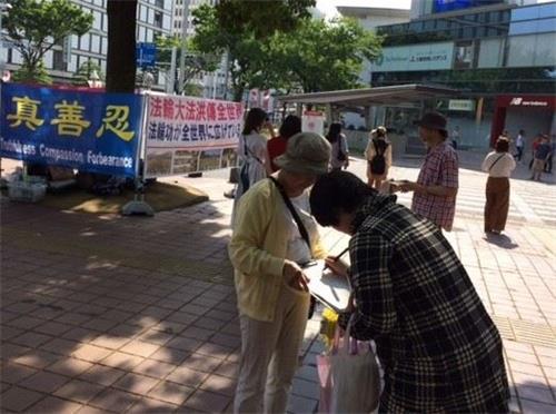 '图1~2:法轮功学员在日本爱知县首府名古屋市举办活动讲真相,庆祝世界法轮大法日。民众明真相后,签名声援法轮功。'
