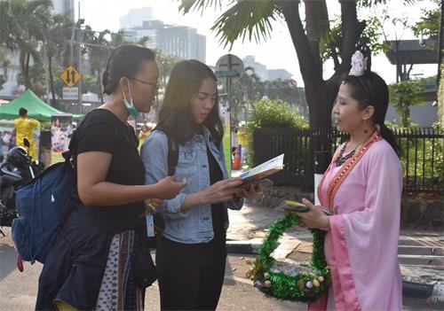 图2~3:路人驻足听法轮功学员讲真相。