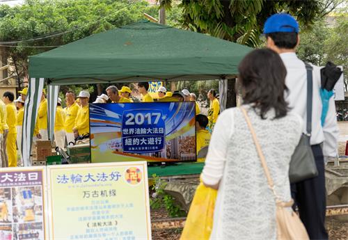 图5~6:2019年5月5日,在高雄桥头糖厂提前庆祝“世界法轮大法日”,民众驻足观看法轮大法洪传世界图片展和电视影片。