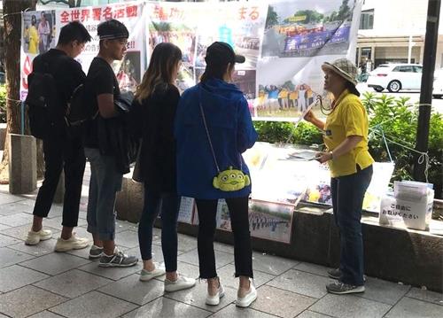 '图1:法轮功学员向观看展板的民众讲真相'