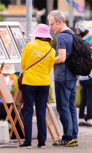 '图11:从瑞士来台旅游的 丹尼先生(Danny,右)观看图片展,透过学员的解说,明白了些大法洪传的情况。'