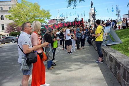 '图14~15:在魁北克市旅游景点兵器广场,游人在认真了解法轮功真相。'