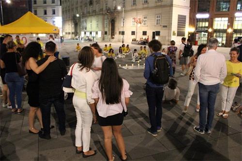 '图1~2:法轮功学员在七月十九日晚烛光守夜 ,吸引许多路人的关注。'