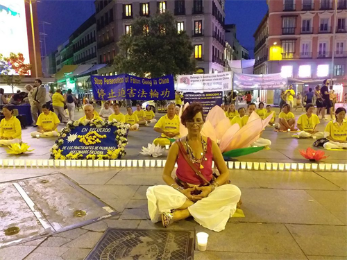 '图3:2019年7月19日,在马德里Callao广场,Vivian Acosta女士和法轮功学员一起,席地而坐,烛光守夜。'
