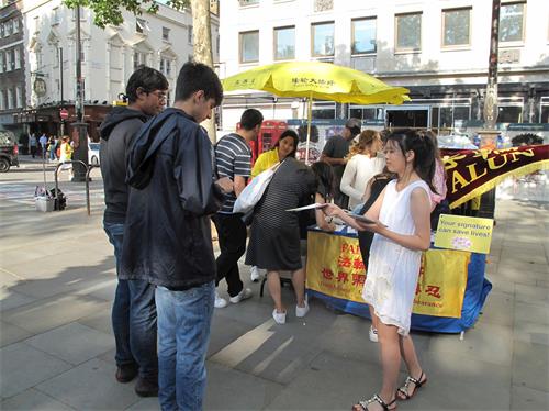 '图17:二零一九年七月二十日,从小就跟着妈妈学法炼功的大法小弟子法童(身穿白色衣裙的女孩)在圣马丁广场向路人发放真相传单。'