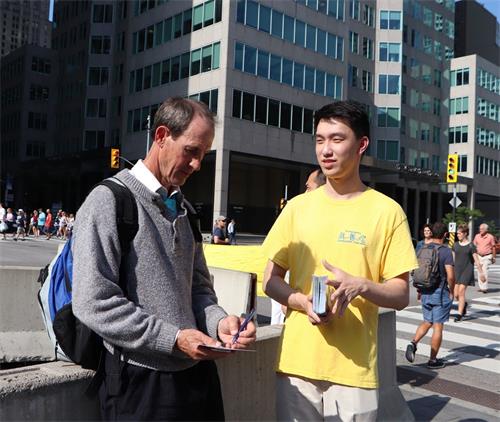 '图9:出生在加拿大在澳大利亚工作的凯文·斯塔尔斯(Kevin Stalls)表示非常支持法轮功学员反迫害。他正在“停止迫害法轮功”的明信片上签名。'