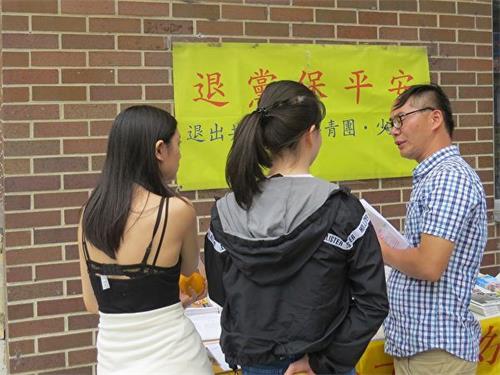 '图1:华裔女孩Hannah(右)与她的朋友Alina静心倾听法轮功真相。'