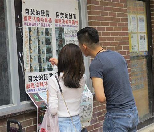 '图2:一位年轻华人在与女友观看海报时,认为中共对法轮功的迫害“没有人性”。'