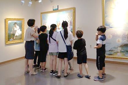 '图6:小学生们在倾听着法轮功学员的解说,观看画作。'