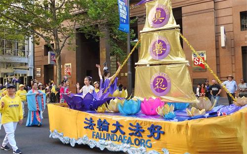 '图7:新学员Kim身着金黄T恤走在花车旁,充满喜悦。'