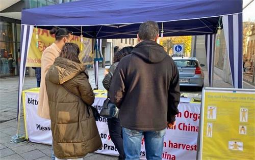 '图1:过往民众驻足在真相桌前了解真相。'