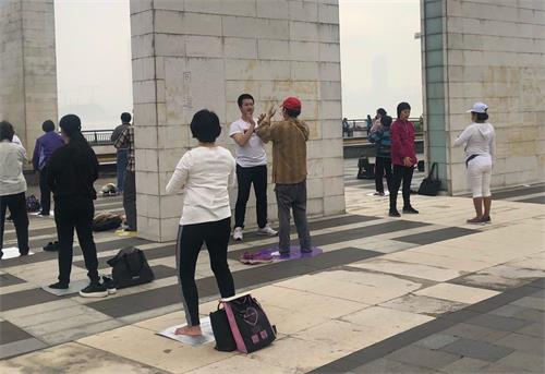 '图2:集体炼功现场有民众来学炼法轮功。'