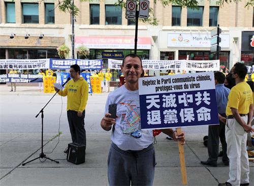 '图6:蒙特利尔市民卡诺(Cano)举起抗议牌子表达对法轮功学员的支持'