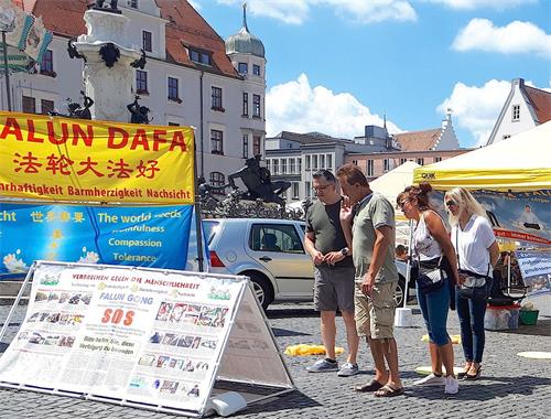 '图1:二零二零年七月十八日,法轮功学员在德国奥格斯堡(Augsburg)的市政厅广场(Rathausplatz)举办信息日活动,吸引了德国民众的关注。'