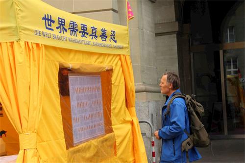 '图4:尼古拉斯(Nicolas)正在仔细观看法轮功的功法介绍图。'