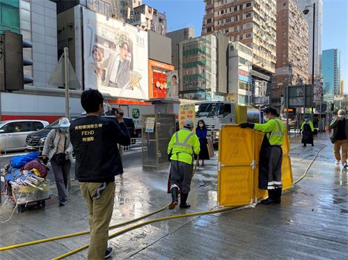 '图1:二零二一年一月二十九日,香港食环署清洁工用水龙头、借故清洗街道,欲阻止法轮功学员开设真相点。'